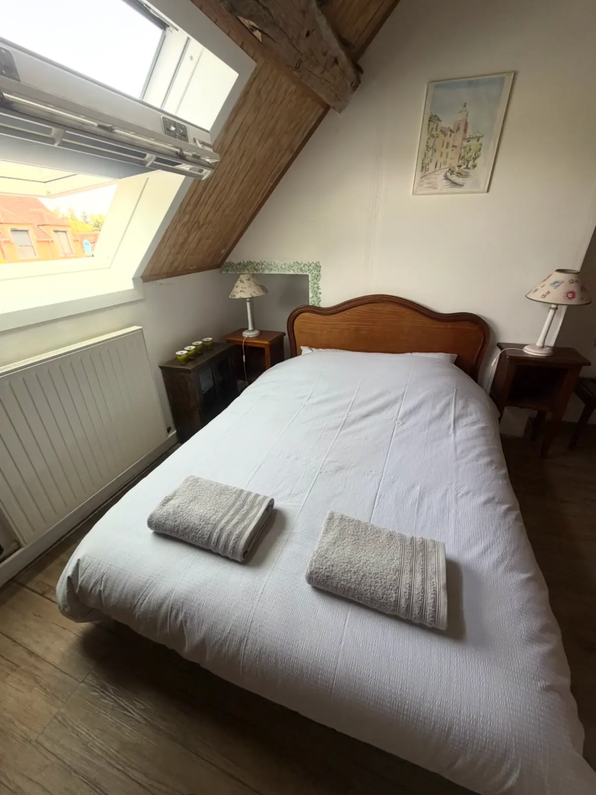 Chambre mansardée sous les poutres, lit blanc avec deux serviettes pliées